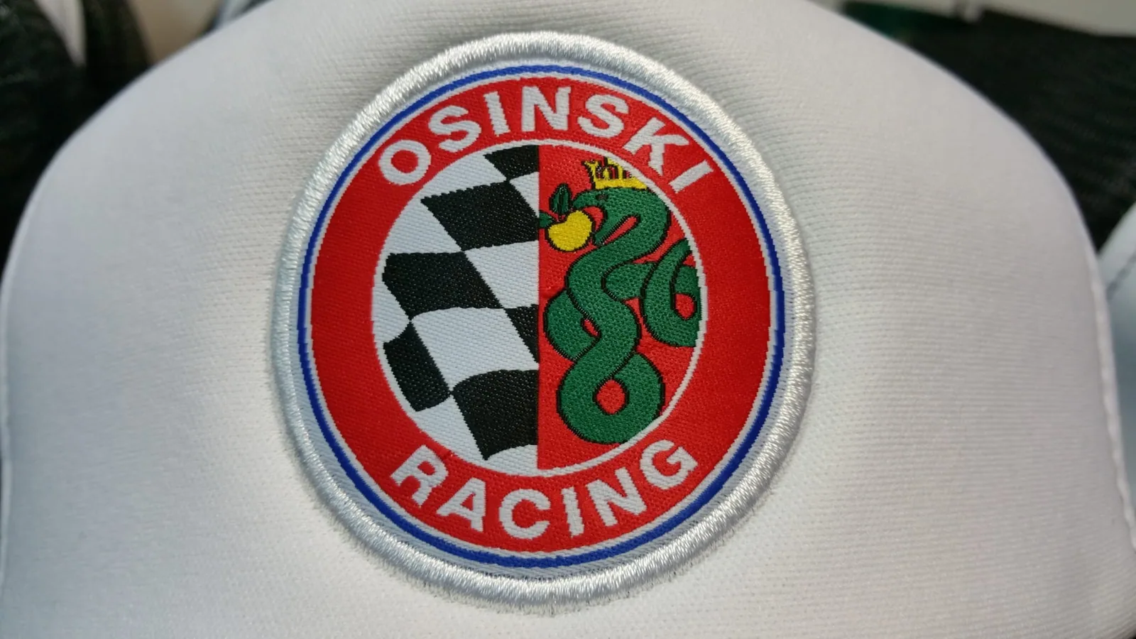 Okrúhla vyšívaná nášivka pretekárskeho tímu na bielej šiltovke