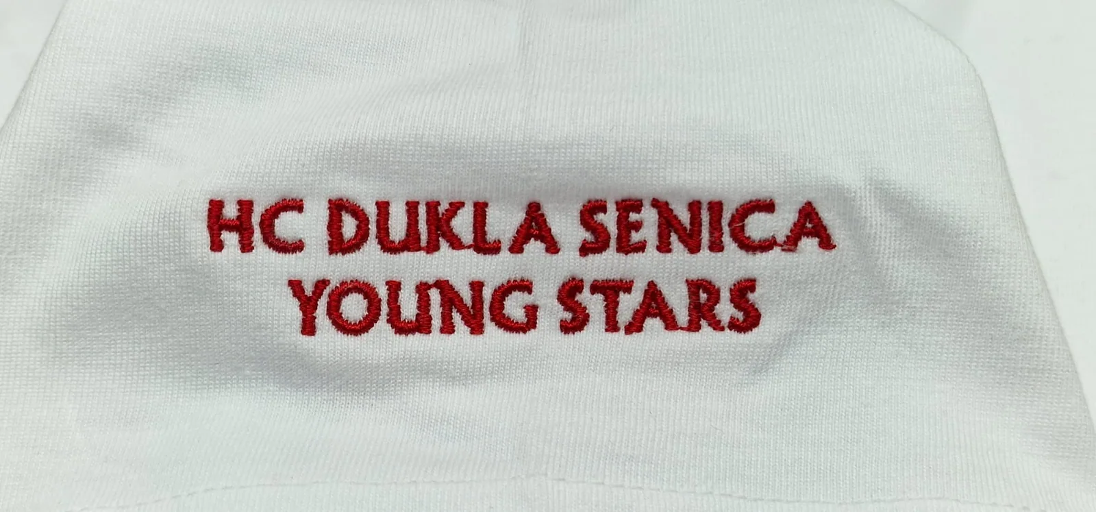 Vyšitý nápis hokejového klubu na bielom tričku
