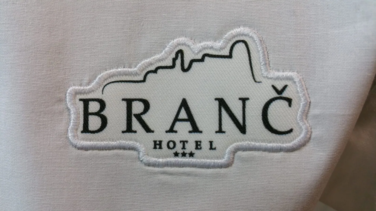 Vyšívané logo hotela na svetlom textile