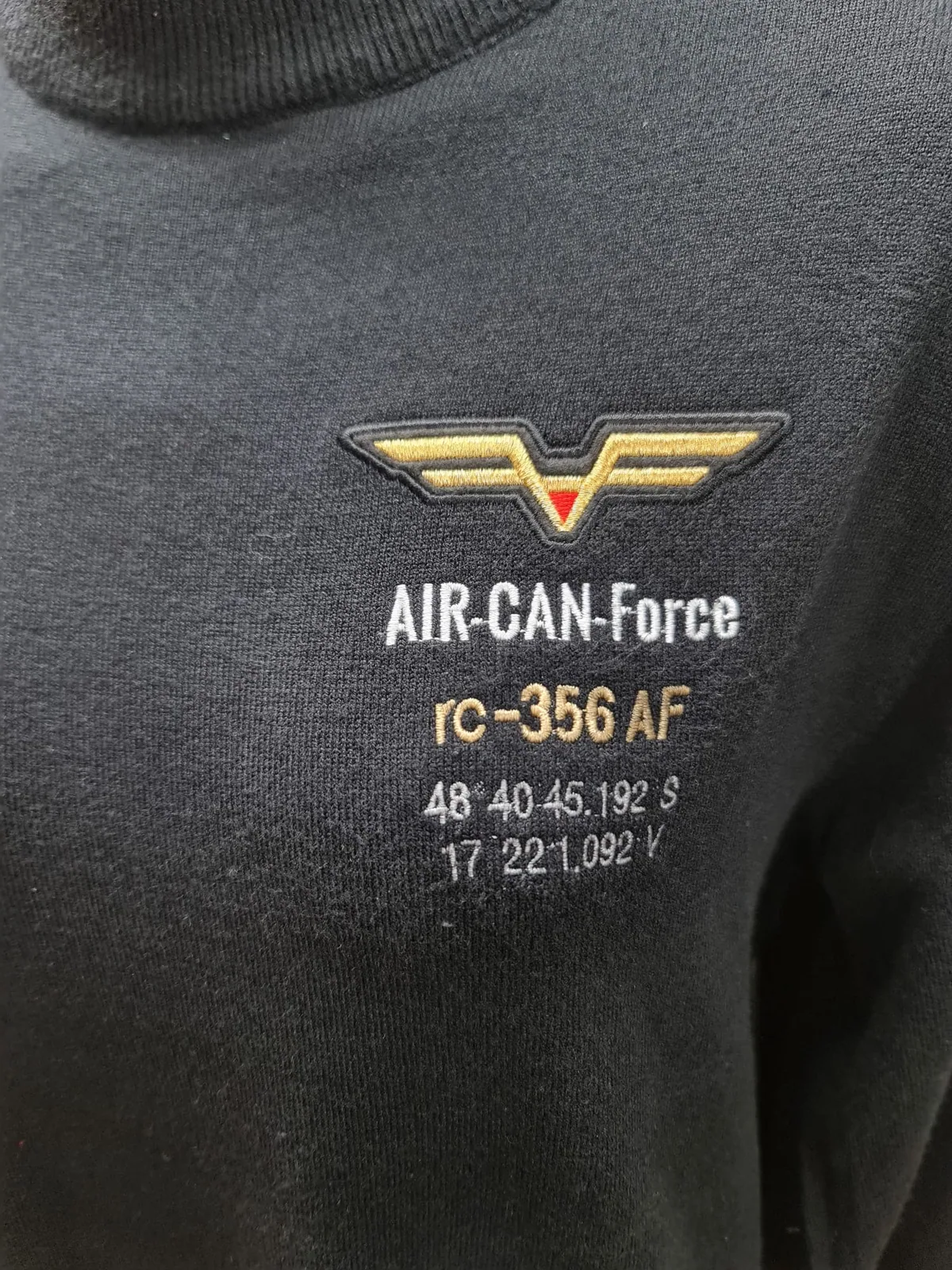 Vyšívané logo so zlatými krídlami na čiernom tričku