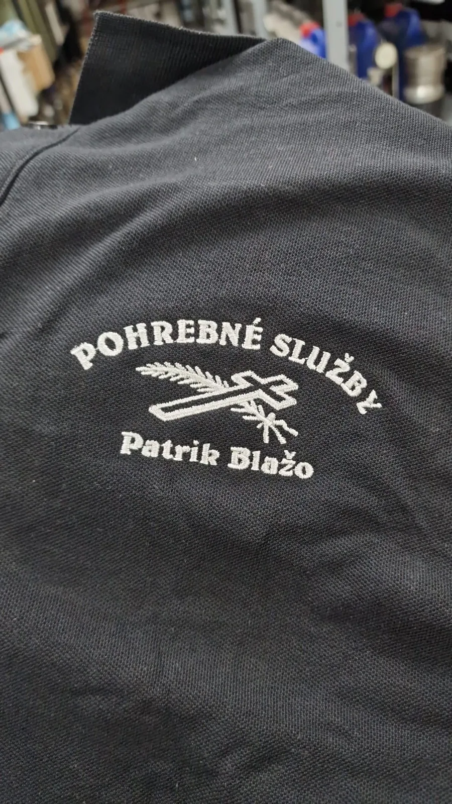 Biele vyšité firemné logo na čiernom tričku