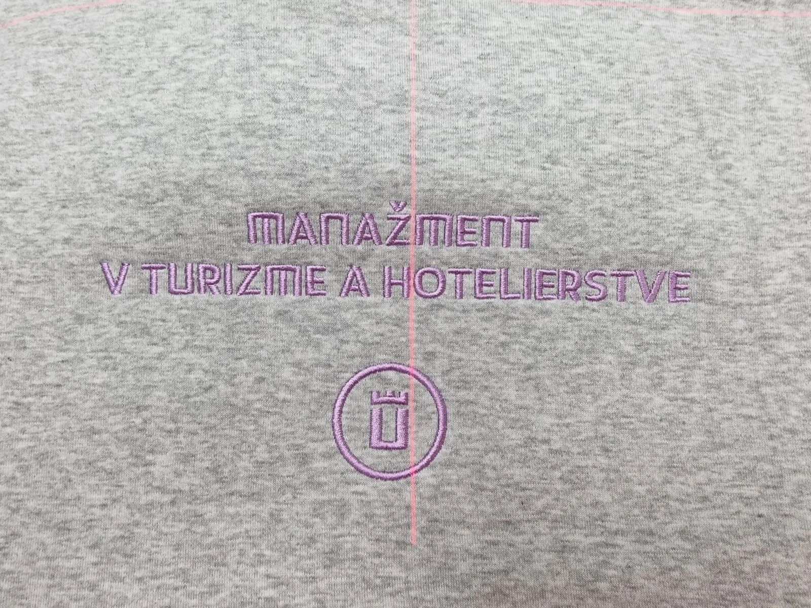 Vyšitý nápis študijného odboru s logom na sivom textile