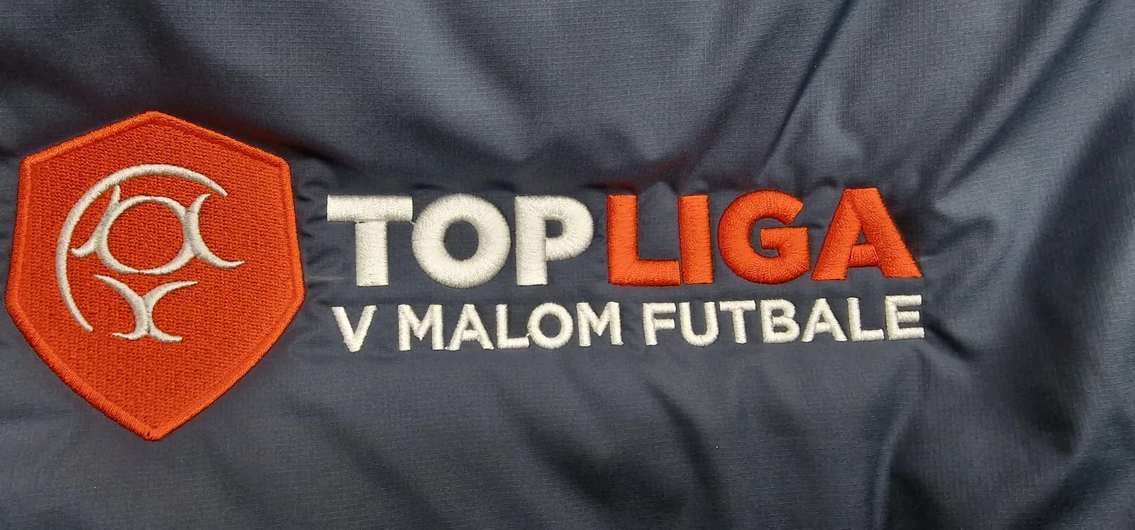 Vyšité logo futbalovej súťaže na čiernej bunde