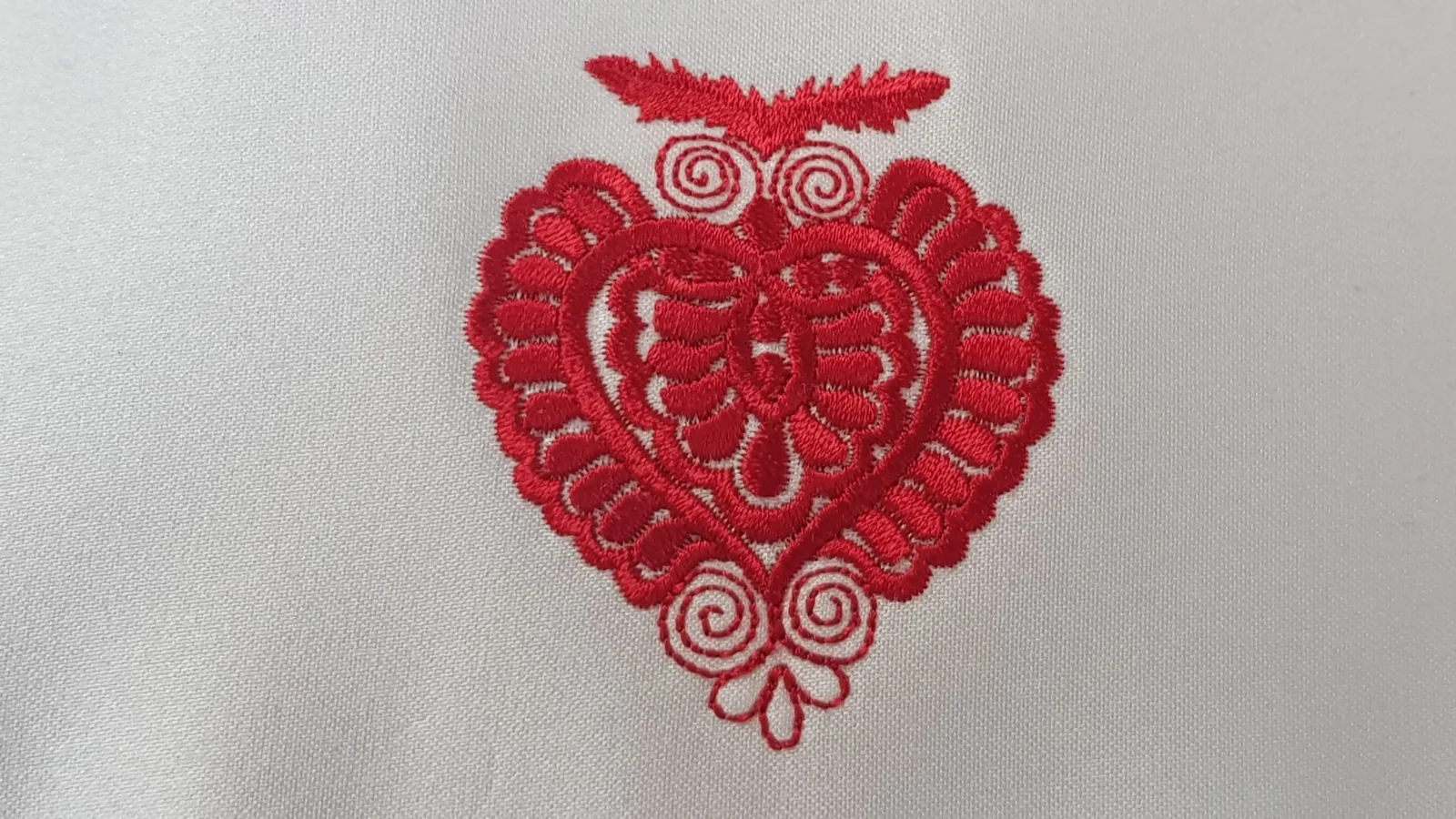Vyšité červené ľudové srdce na svetlom textile