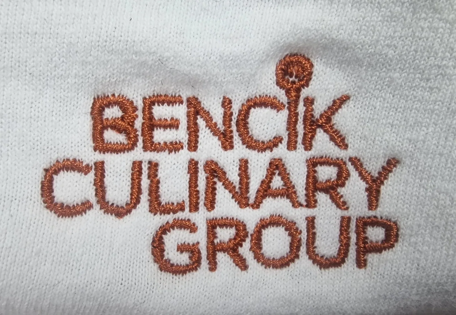 Vyšité logo gastronomickej firmy hnedou niťou