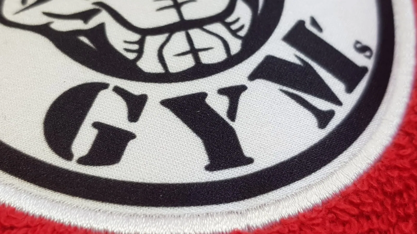 Detail nášivky fitnescentra na červenom froté uteráku