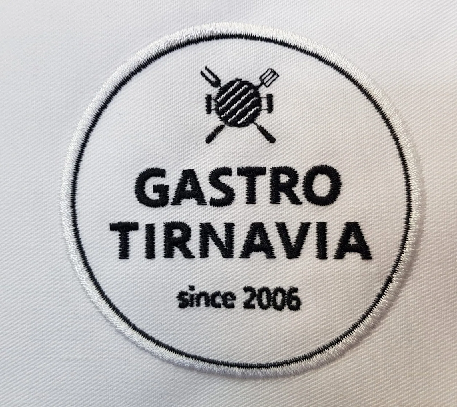 Okrúhla vyšitá nášivka gastro firmy na bielom textile