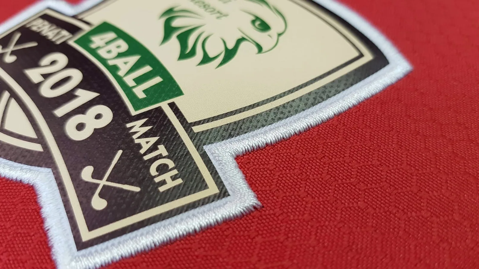 Detail nášivky golfového turnaja na červenom textile