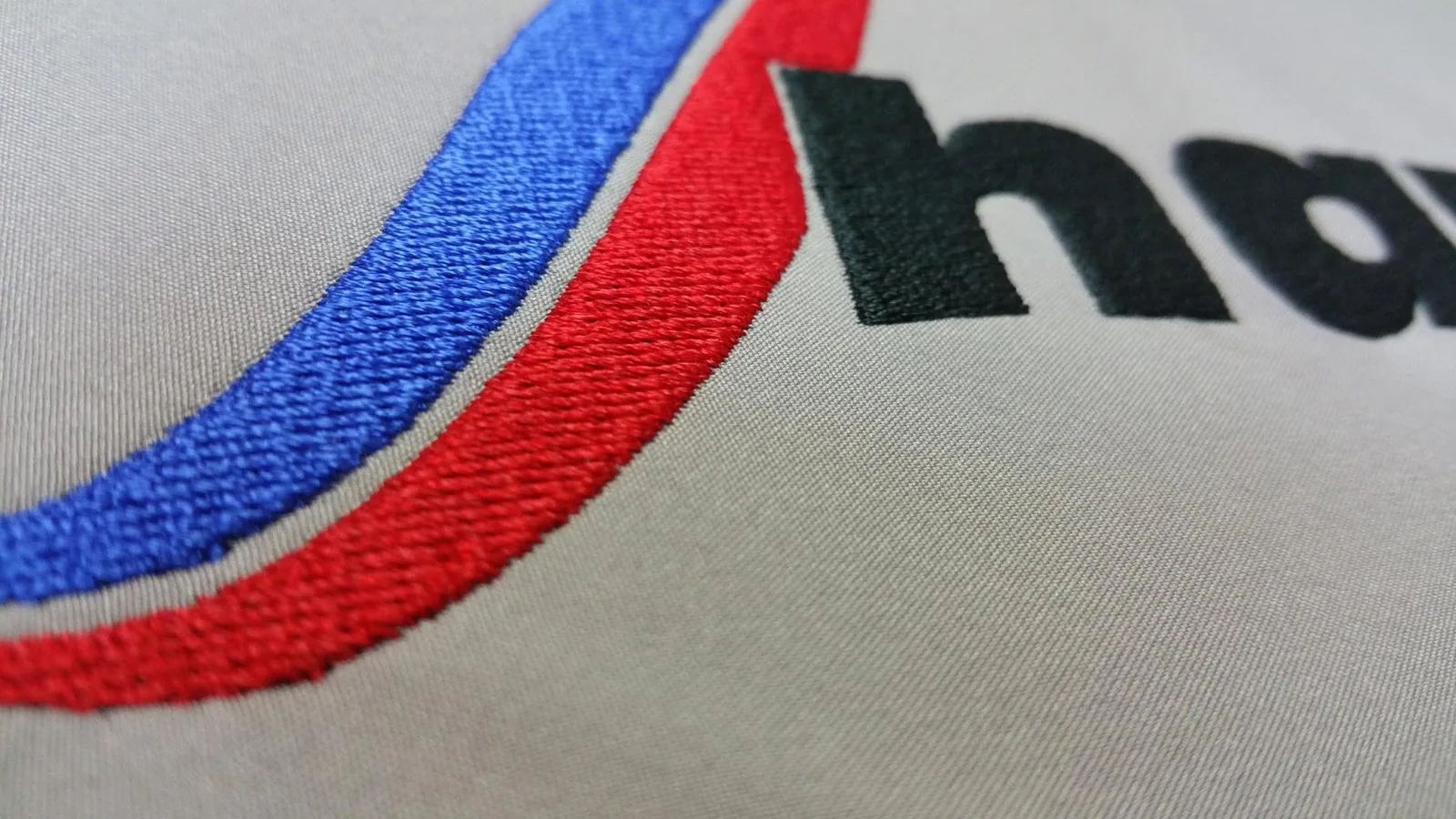 Vyšitá trikolóra a logo na sivom textile
