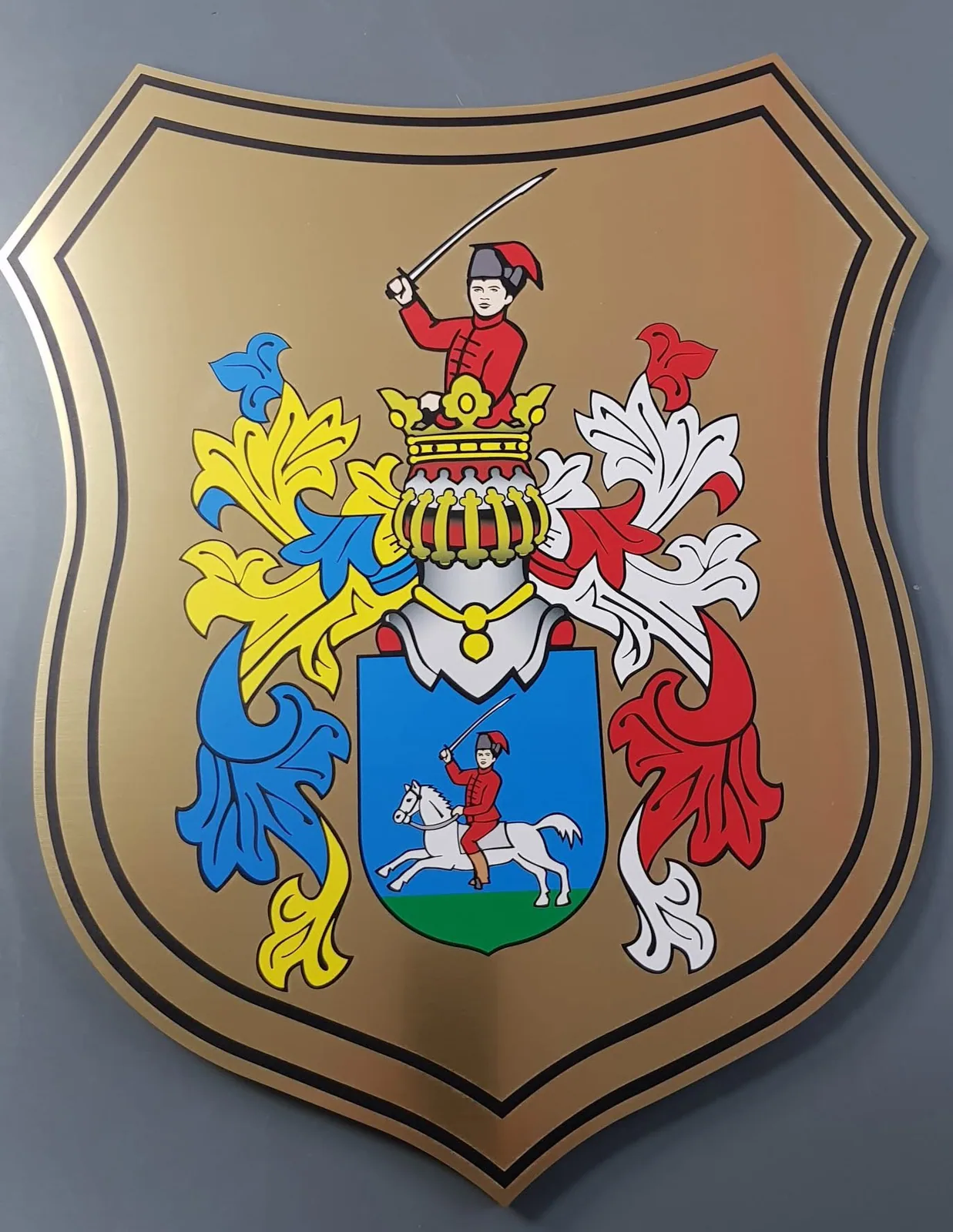 Kovová tabuľa v tvare štítu s farebným erbom obce