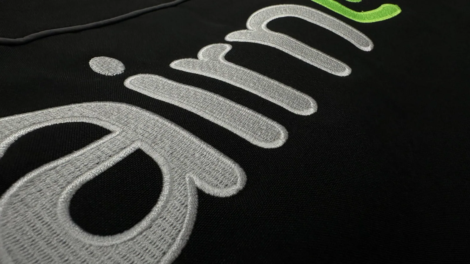 Detail plastickej výšivky nápisu na čiernom textile