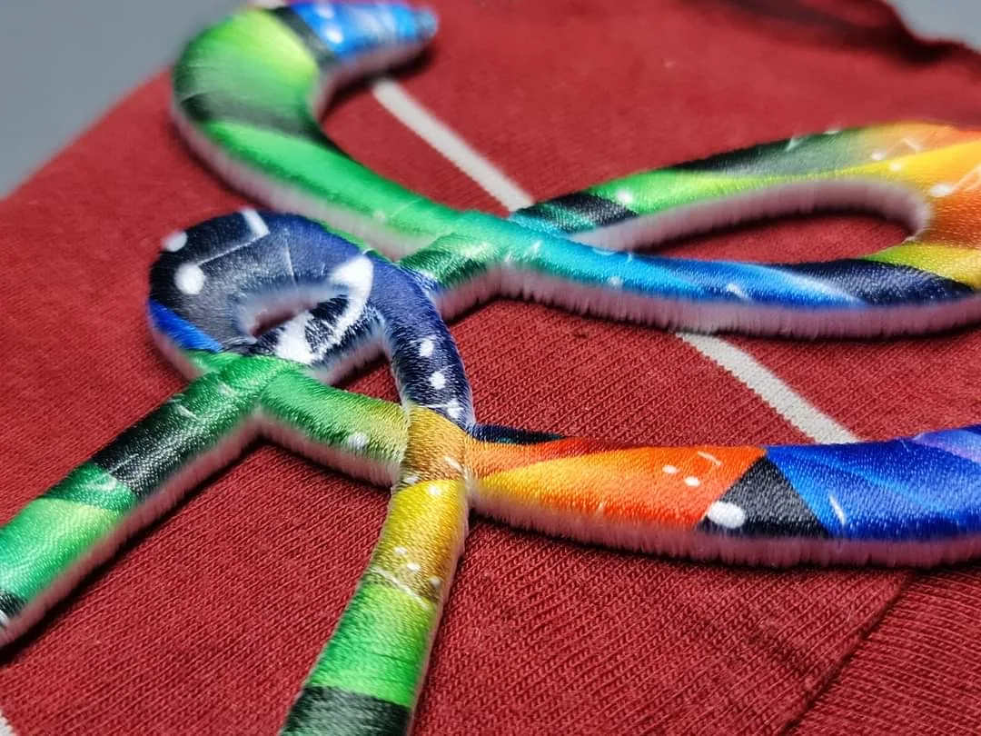Dúhový plastický motív na červenom textile