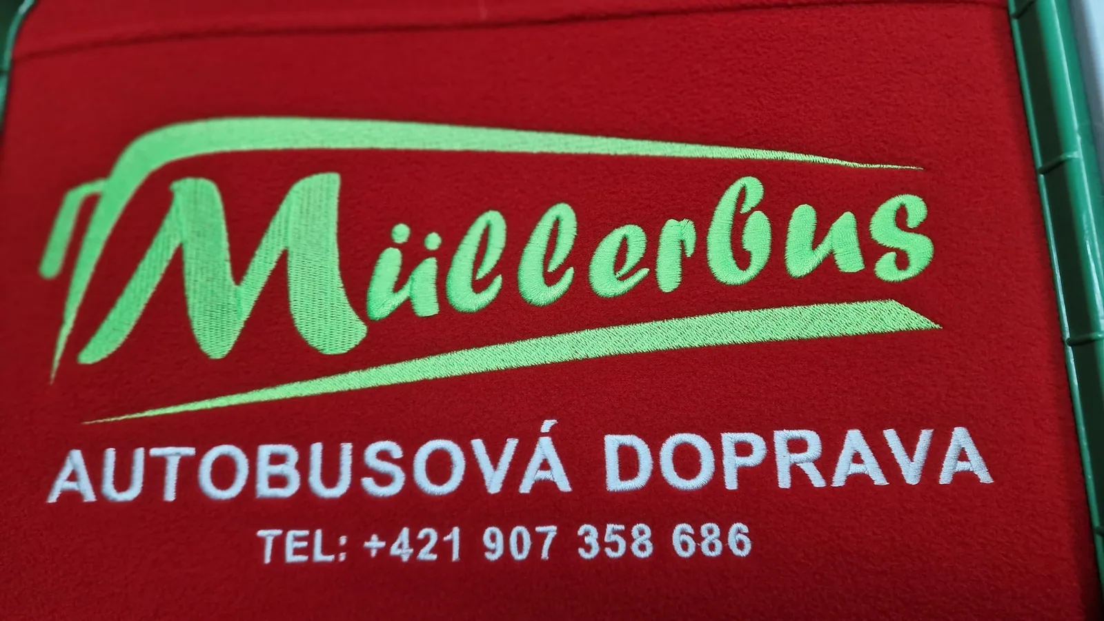 Vyšité logo autobusovej dopravy na červenom textile