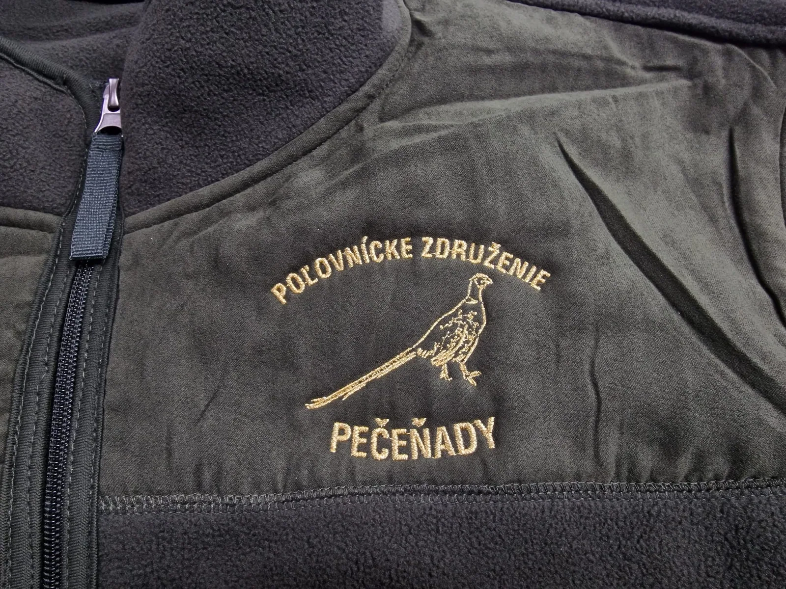 Vyšité logo poľovníckeho združenia s bažantom na flísovej bunde