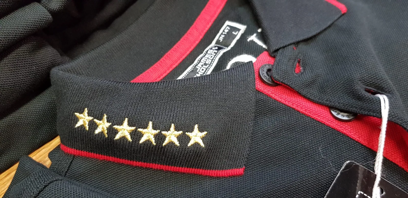 Päť zlatých vyšitých hviezd na golieri čiernej polokošele
