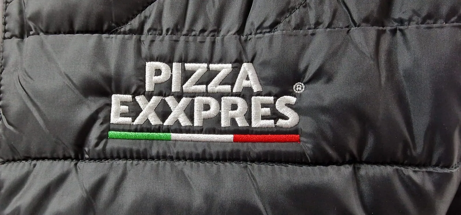Vyšité logo pizzerie na čiernej prešívanej bunde