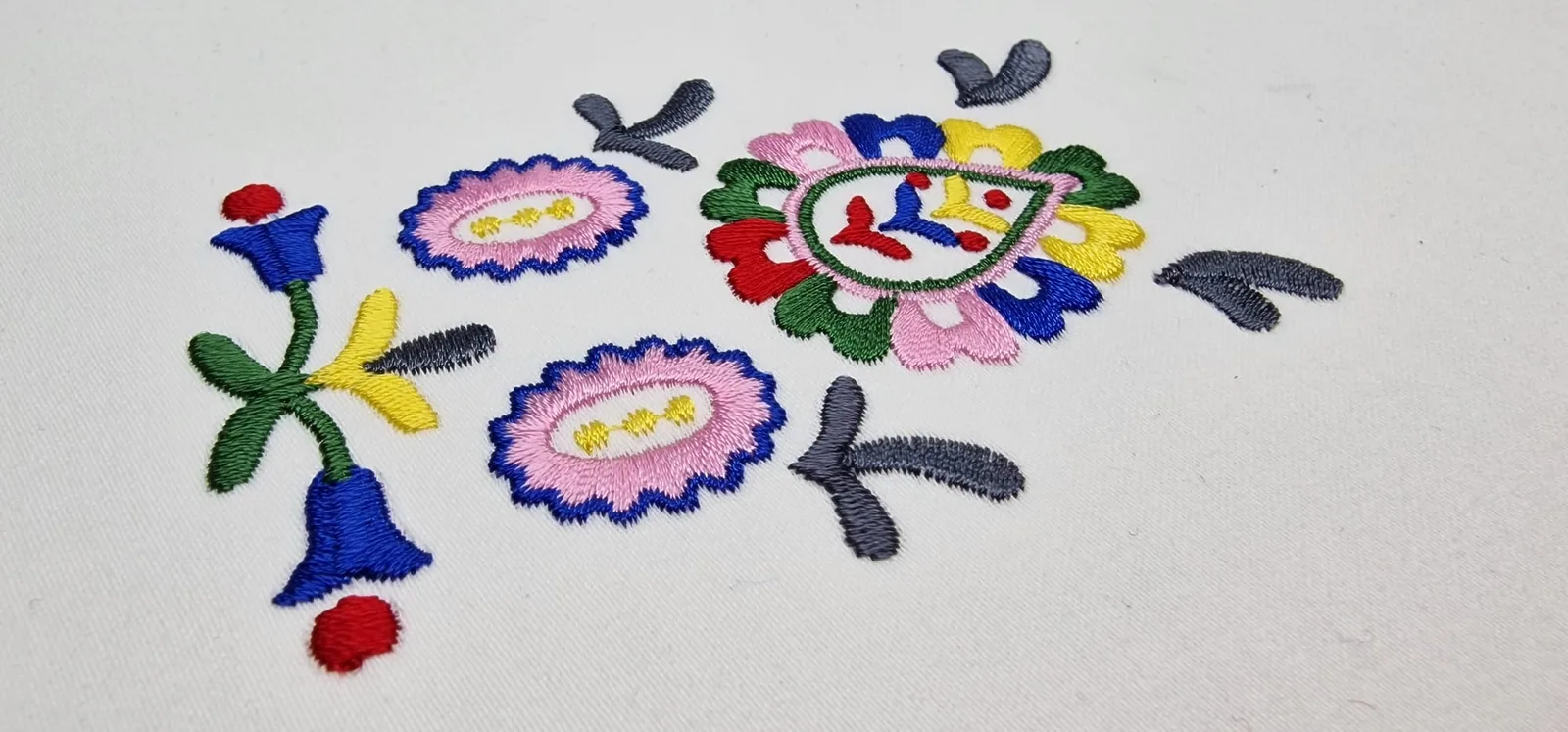 Farebná výšivka ľudových kvetinových motívov na bielom textile