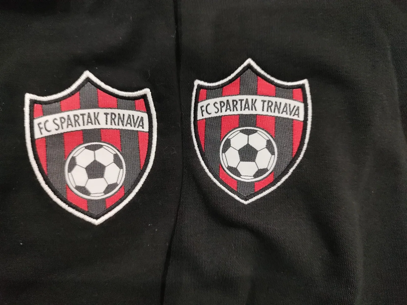 Dva vyšité erby futbalového klubu na čiernom textile