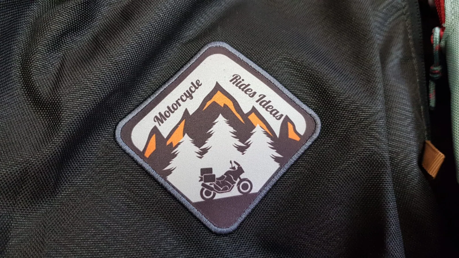 Nášivka s motívom hôr a motorky na čiernej bunde